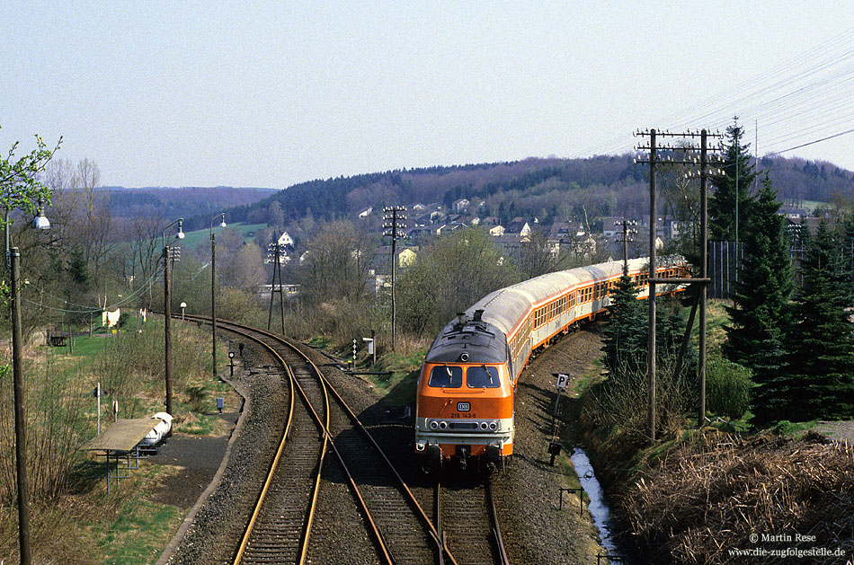 Am 3.5.1986 fuhr die 218 143 (Bw Hagen 1) mit der CB6426 (Meinerzhagen - Kln) in den Bahnhof Marienheide ein. Whrend der Reisezugverkehr zwischen Meinerzhagen und Brgge einen Monat spter eingestellt wurde, verblieben noch fr ein Jahr drei werktgliche Zugpaare zwischen Meinerzhagen und Gummersbach. Links ist die Strecke nach Remscheid Lennep zu sehen, auf der bereits am 1.6.1985 der Reisezugverkehr eingestellt wurde.